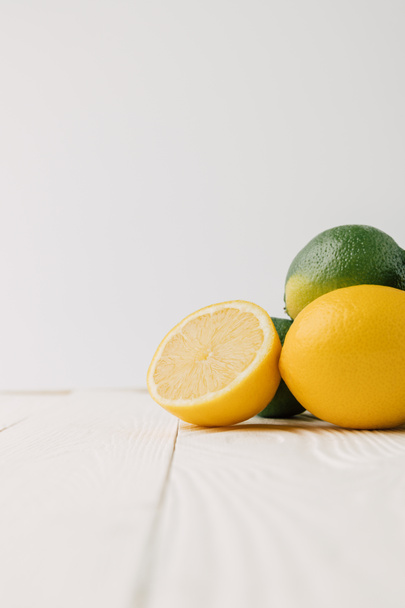 Green limes and lemons on white wooden background - Fotografie, Obrázek