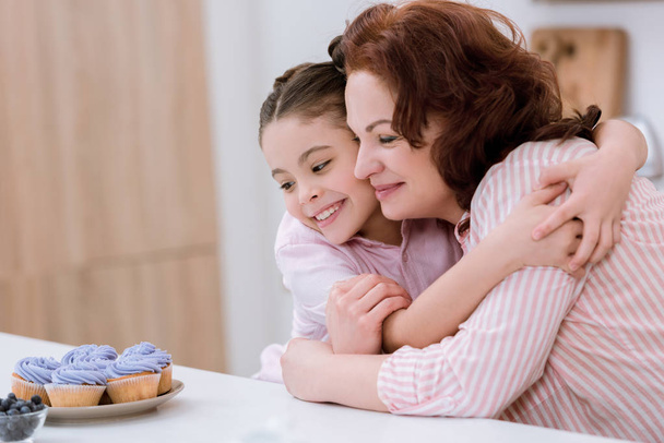 syleilee isoäiti ja pieni lapsenlapsi katsomassa kermainen cupcakes
 - Valokuva, kuva