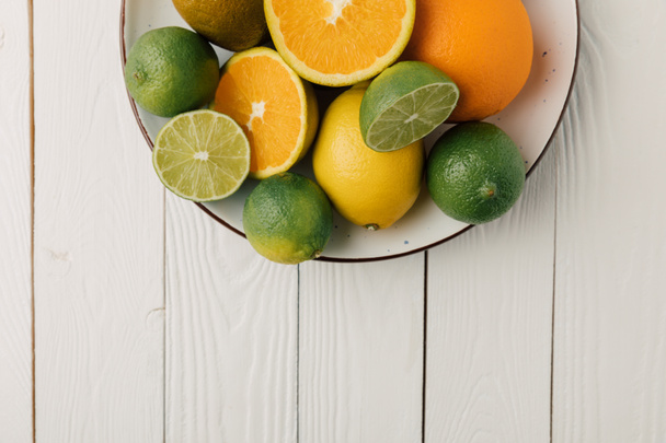 Citrus fruits on plate on white wooden background - Photo, Image