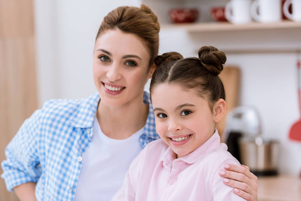 close-up portrait of young happy mother and daughter looking at camera - Photo, image