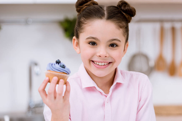 close-up portrait of little child holding blueberry cupcake - Fotó, kép