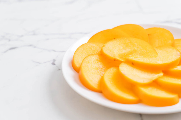 sliced persimmon on plate - Фото, зображення