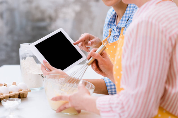 plan recadré de femmes utilisant la tablette ensemble à la cuisine pendant la cuisson
 - Photo, image