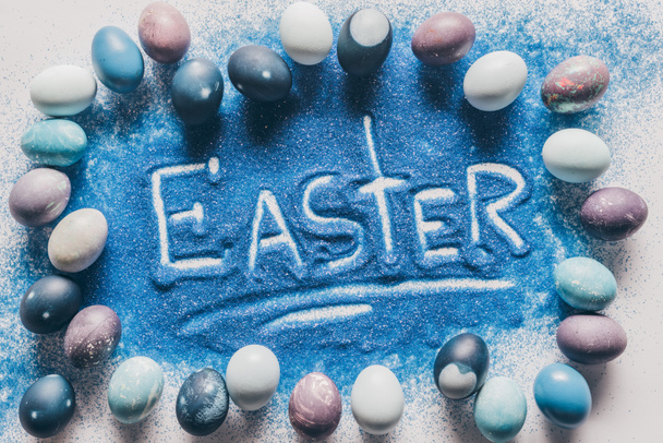 vue du dessus du panneau de Pâques en sable bleu avec des œufs peints sur blanc
 - Photo, image