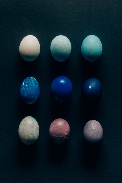 collection of nine colored painted easter eggs on dark surface - Fotoğraf, Görsel