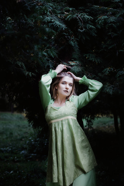Mavka. Een mooie vrouw in een groene jurk loopt door het bos. - Foto, afbeelding