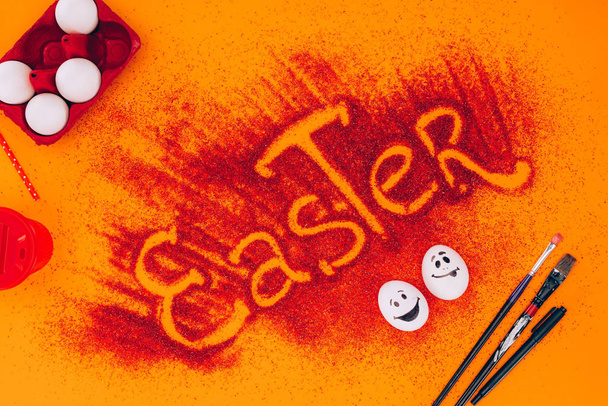 vista superior del letrero de Pascua hecho de arena roja con huevos de pollo en naranja
 - Foto, Imagen
