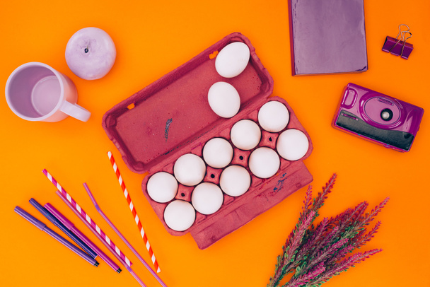 pohled shora slepičí vejce ve fialové vajíčko zásobníku pro velikonoční Malování izolované na oranžové - Fotografie, Obrázek