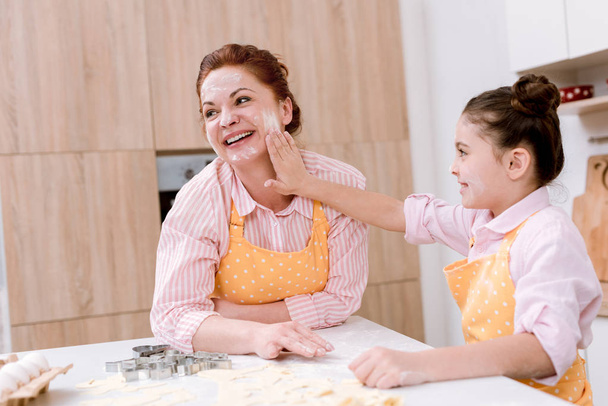 happy grandmother and little granddaughter playing with flour at kitchen while cooking - 写真・画像