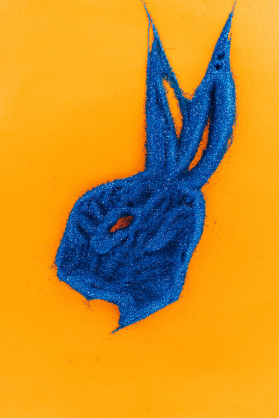 вид на голубого пасхального кролика из песка, изолированного на оранжевом
 - Фото, изображение