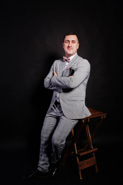 Handsome man in gray suit with microphone against black backgrou - Fotografie, Obrázek