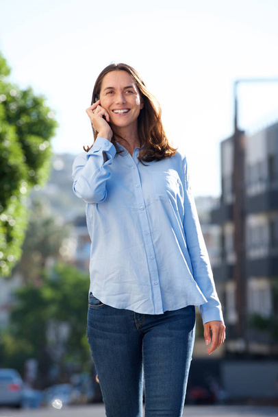Portret Kobieta w średnim wieku chodzenia poza i rozmowy z telefonów komórkowych - Zdjęcie, obraz