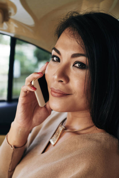 Face of attractive Thai woman having phone talk on the way home - Photo, Image