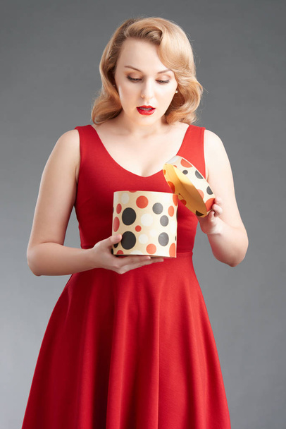 Bella donna curiosa in abito rosso apertura scatola regalo rotonda
 - Foto, immagini