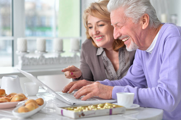 feliz pareja de ancianos con portátil en casa - Foto, Imagen