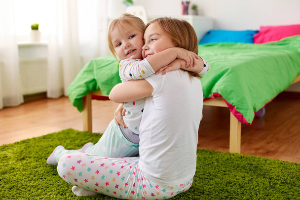 happy little girls or sisters hugging at home - Foto, Imagem