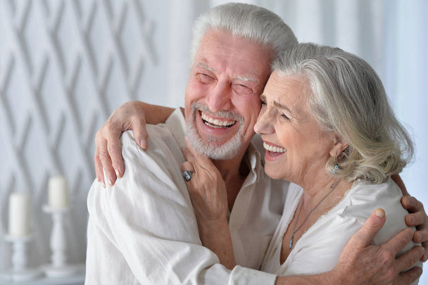 Porträt eines glücklichen Senioren-Paares, das sich zu Hause umarmt - Foto, Bild