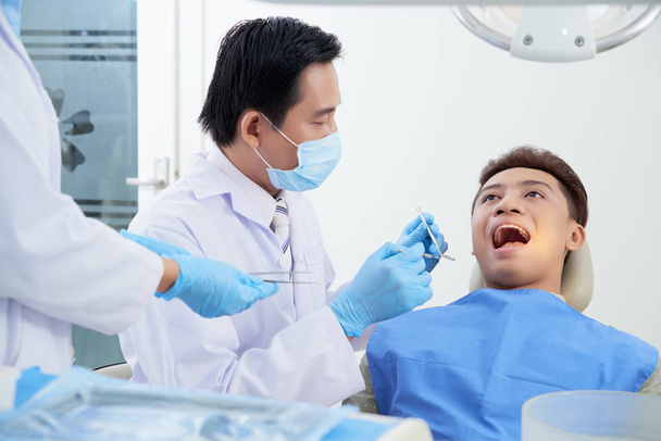 Un joven paciente vietnamita está listo para examinarse los dientes. Concepto de prevención de caries
 - Foto, Imagen