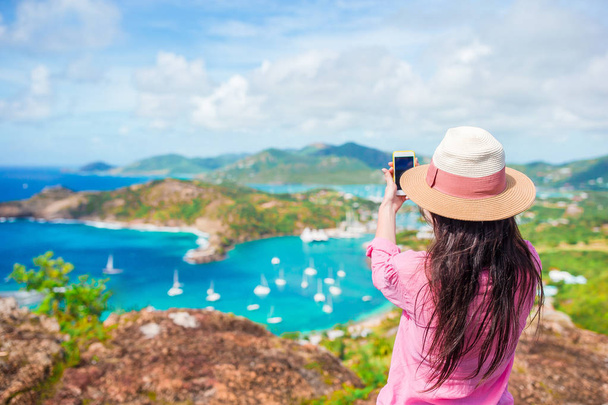 Mladí turistické žena dělat Foto z angličtiny přístavu od Shirley Heights, Antigua, paradise bay na tropický ostrov v Karibském moři - Fotografie, Obrázek