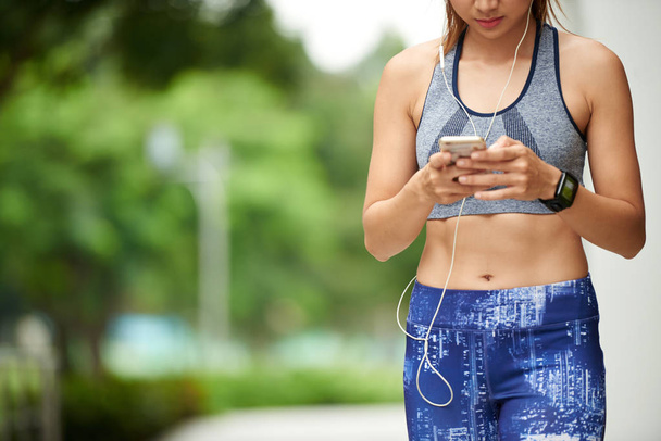Cropped image of fit woman checking application in her smartphone - Fotografie, Obrázek