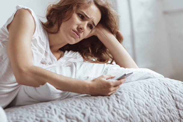 Femme émotionnellement épuisée devenir déprimé tout en utilisant un smartphone
 - Photo, image