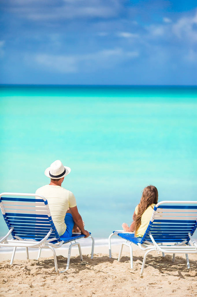 Padre e hija manos arriba en la playa sentados en chaise-longue
 - Foto, Imagen