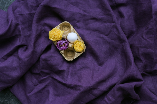 Chicken egg and flowers in carton on textile background - Φωτογραφία, εικόνα