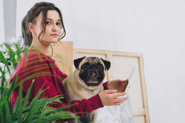 Attractive young girl using tablet and holding dog at home - Fotoğraf, Görsel