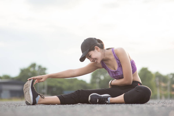 Asya kadın sporcu bir egzersiz minderi ve str üzerinde oturan gülümseyen - Fotoğraf, Görsel