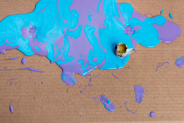 Broken quail egg in paint on cardboard background - Foto, imagen