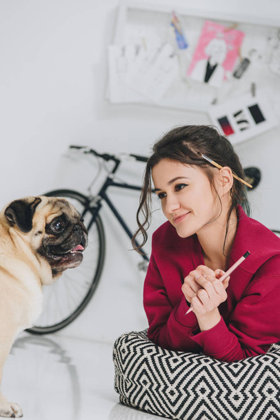 Young woman artist looking at pug dog - Foto, Imagen