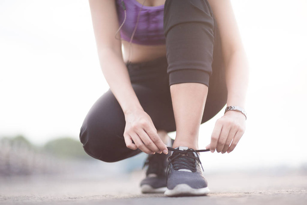 mladá žena běžec vázání tkaničky před jogging stojící na fo - Fotografie, Obrázek