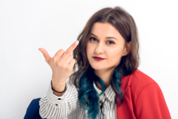 Νεαρή γυναίκα δείχνει μεσαίο δάχτυλο σε λευκό φόντο - Φωτογραφία, εικόνα