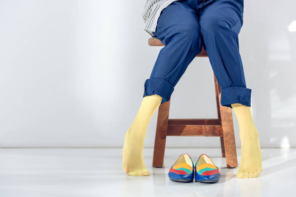 Close-up view of woman sitting on chair with legs in yellow socks - Фото, изображение
