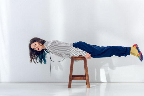 Young girl lying on wooden chair - Valokuva, kuva
