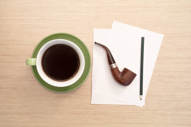 eine grüne Tasse Kaffee auf dem Tisch und leeres Laken, Bleistift, Pfeifenrauchen - Foto, Bild