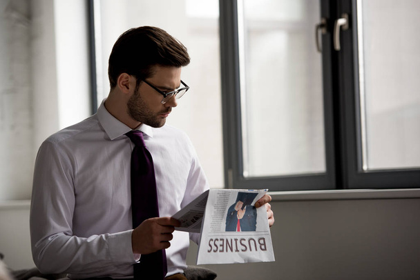View of young businessman in glasses reading newspaper  - Фото, изображение