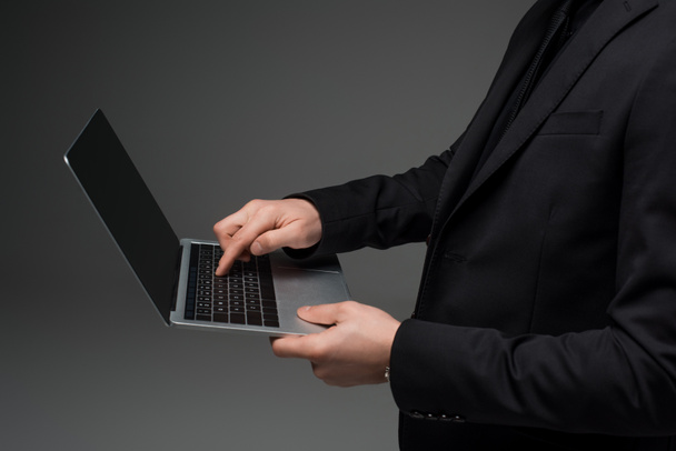 Vue partielle de l'homme d'affaires tenant un ordinateur portable dans des mains isolées sur gris
 - Photo, image