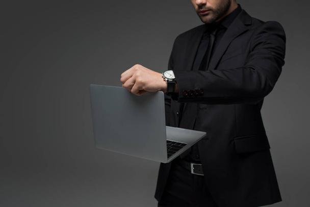 Обрізаний вид стильного бізнесмена з ноутбуком в руках ізольовано на сірому
 - Фото, зображення