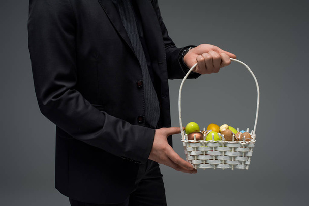 Vista parcial de las manos masculinas sosteniendo cesta con frutas aisladas en gris
 - Foto, imagen