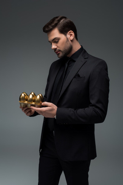 グレー、イースター概念に分離された金の卵を保持している男性のプロフィール - 写真・画像