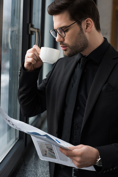 Empresario bebiendo café y sosteniendo periódico
  - Foto, Imagen