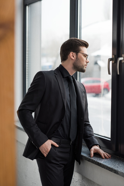 A fiatal üzletember keresi ablakból oldalnézete - Fotó, kép