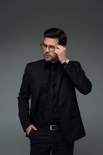 Young stylish man in glasses standing isolated on grey  - Foto, afbeelding