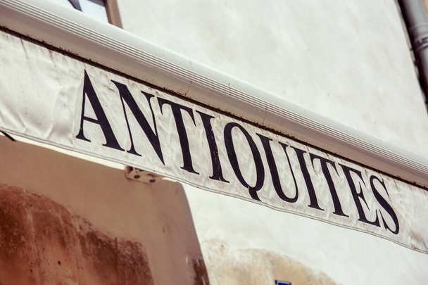 A slanted closeup of sign - "Antiques" ("Antiquites" in French). - Photo, Image