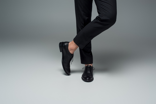 Partial view of male legs in black formal shoes on grey - Fotoğraf, Görsel