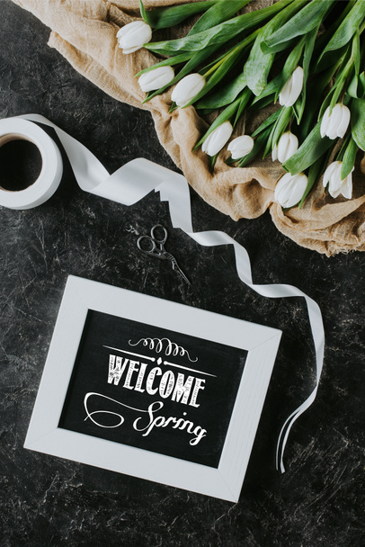 pohled shora bílé tulipány, pásu karet a přivítejte jaro nápis v rámu na černém povrchu - Fotografie, Obrázek