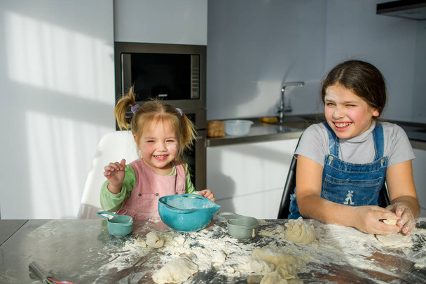 Dvě malé holčičky jsou vaření něco v kuchyni. - Fotografie, Obrázek