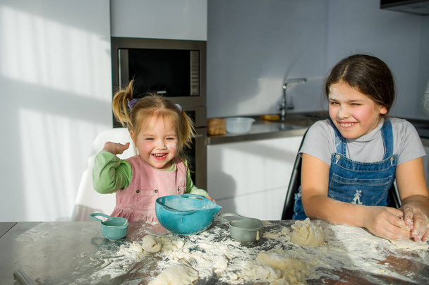 Two little girls are cooking something in the kitchen. - Фото, зображення