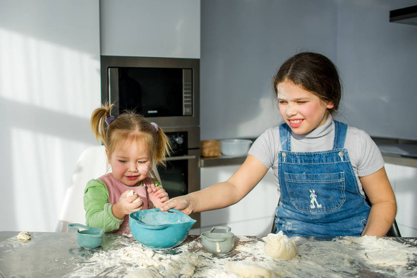 Две маленькие девочки готовят что-то на кухне.
. - Фото, изображение